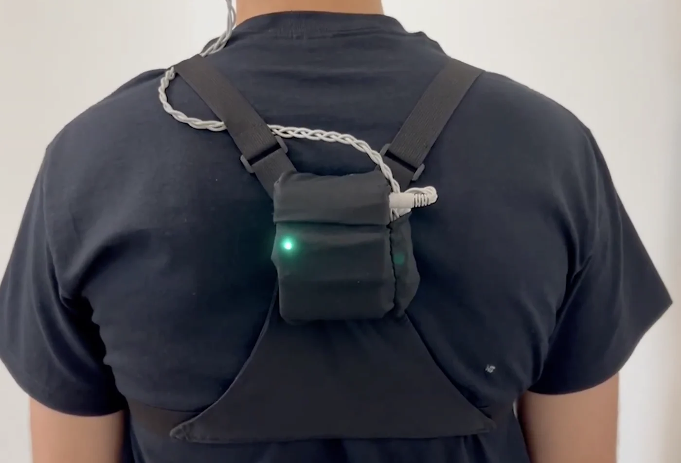 The processing unit worn on the upper back, with the braided electrode lead routed over the shoulder