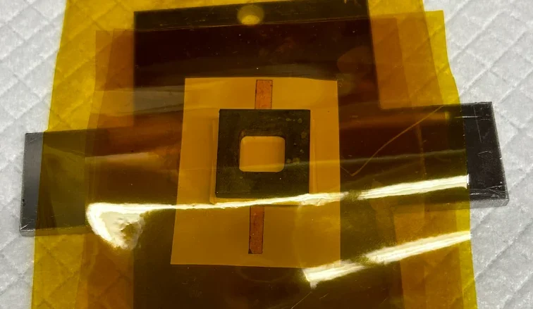 Jig plate loaded with a layered stack, taped in Kapton, ready for the press
